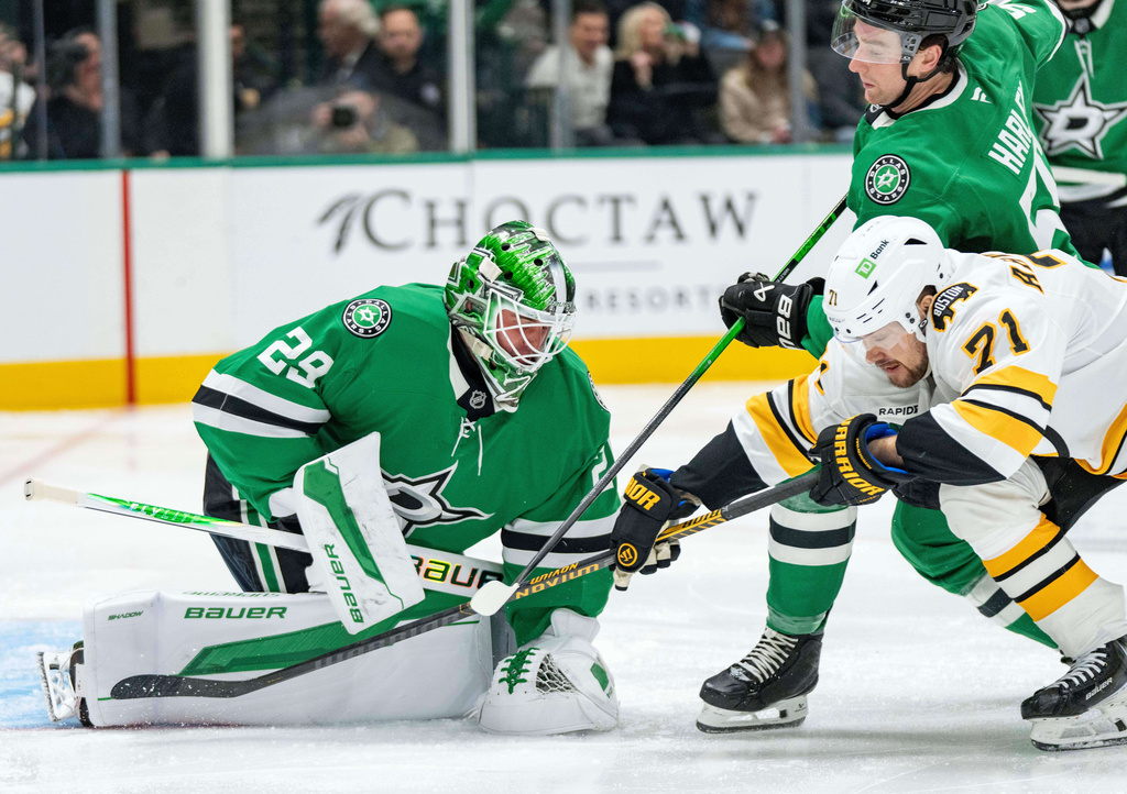 Dallas Stars goaltender Jake Oettinger (29) covers up the puck as Boston Bruins left wing Viktor Arvidsson (71) tangles with Stars defenseman Thomas Harley during the second period of an NHL hockey game, Tuesday, Jan. 20, 2026, in Dallas. (AP Photo/Jeffrey McWhorter)
