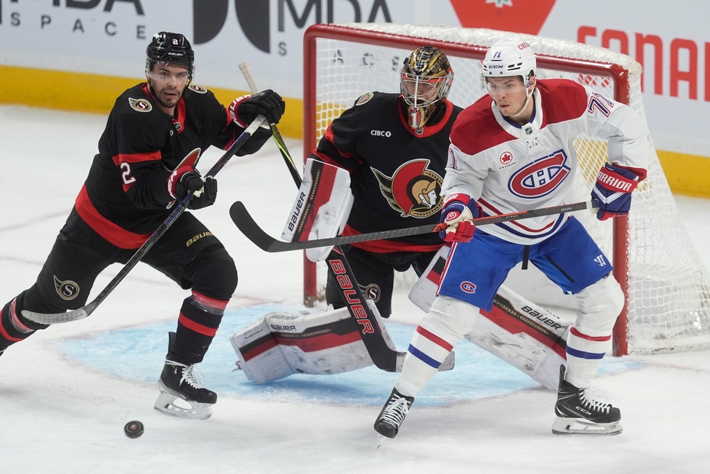 Montreal Canadiens centre Jake Evans (71) tries to tip the puck past Ottawa Senators goaltender Leevi Merilainen (1) as he is pressured by Senators defenceman Artem Zub (2) during the first period of an NHL game, in Ottawa, Saturday, Jan. 17, 2026. (Adrian Wyld/The Canadian Press via AP)