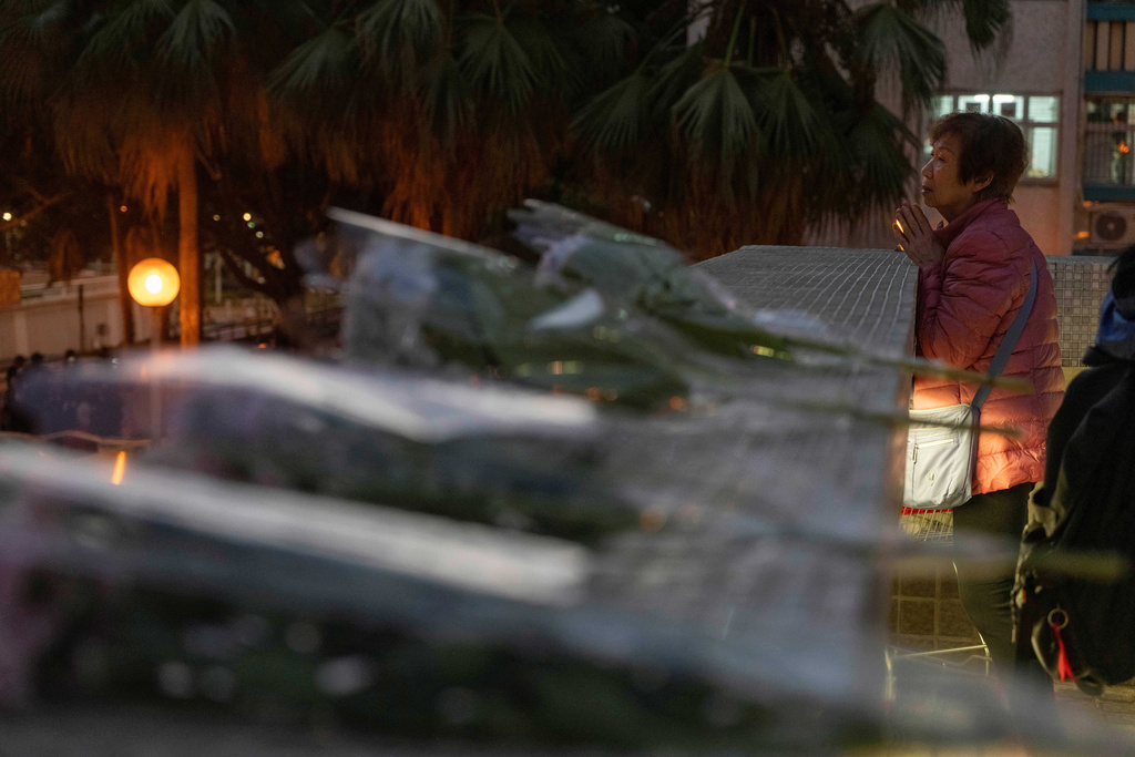 A woman prays near flowers laid to mourn the victims of the deadly Wednesday fire at Wang Fuk Court, a residential estate in the Tai Po district of Hong Kong's New Territories on Saturday, Nov. 29, 2025. (AP Photo/Ng Han Guan)