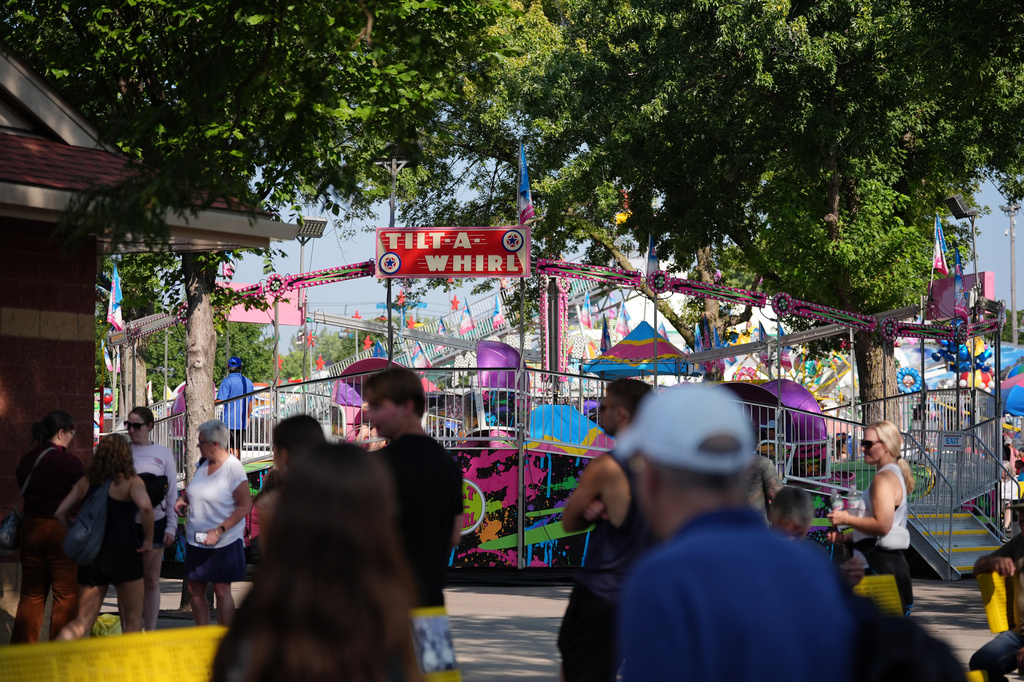 Fairgoers pass the Tilt-A-Whirl, Thursday, Aug. 27, 2026, at the Minnesota State Fair in Falcon Heights, Minn. (AP Photo/Ellen Schmidt)