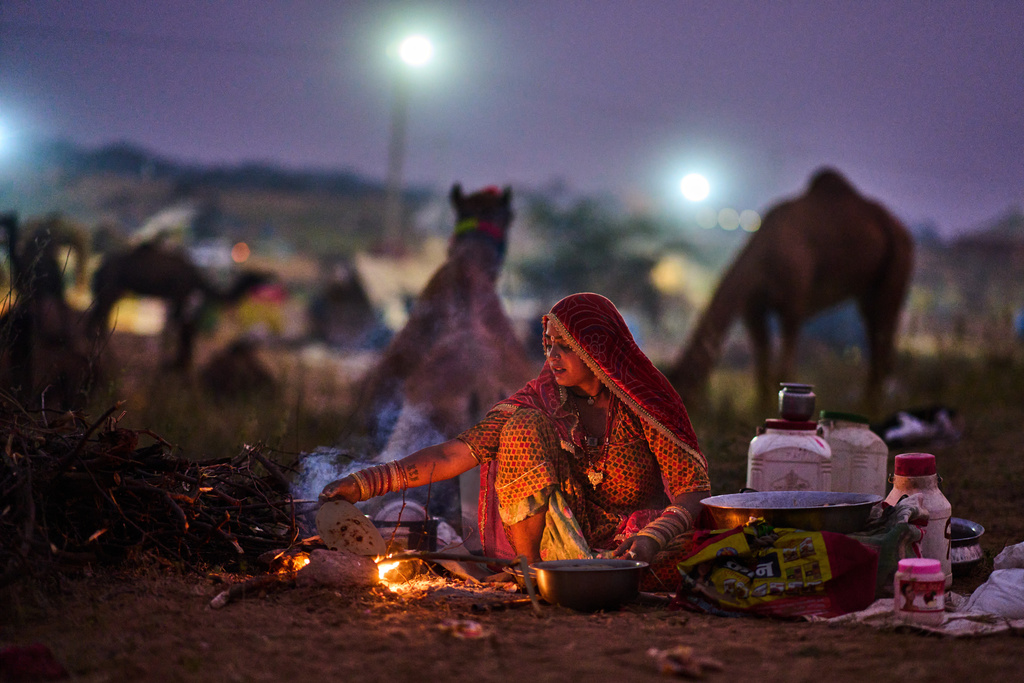 A woman prepares food at the annual cattle fair in Pushkar, in the western Indian state of Rajasthan, Sunday, Oct. 26, 2025. (AP Photo/Rajesh Kumar Singh)