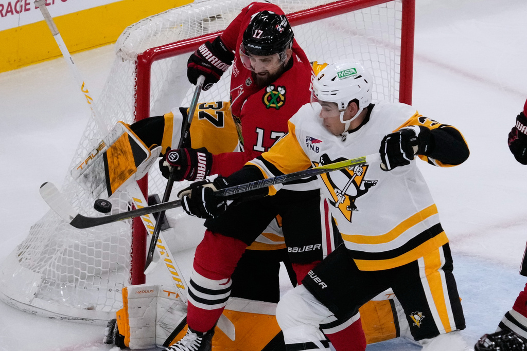 Chicago Blackhawks left wing Nick Foligno (17) battles for the puck against Pittsburgh Penguins goaltender Arturs Silovs, left, and defenseman Jack St. Ivany, right, during the first period of an NHL hockey game in Chicago, Sunday, Dec. 28, 2025. (AP Photo/Nam Y. Huh)