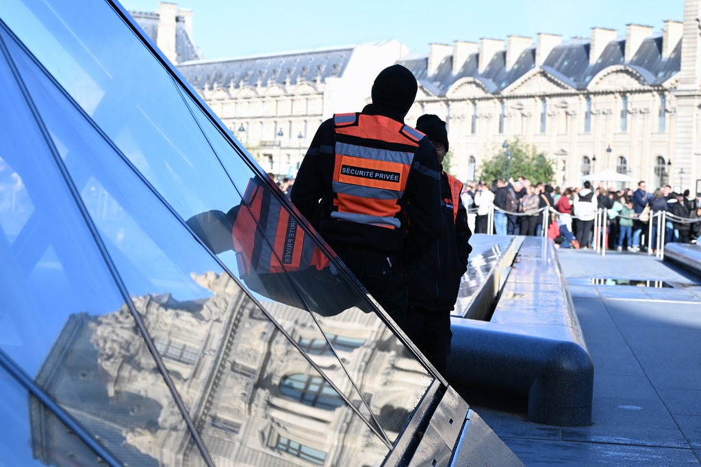 Private security members watch people queueing outside the Louvre museum, Thursday, Oct. 30, 2025 in Paris. (AP Photo/Emma Da Silva)