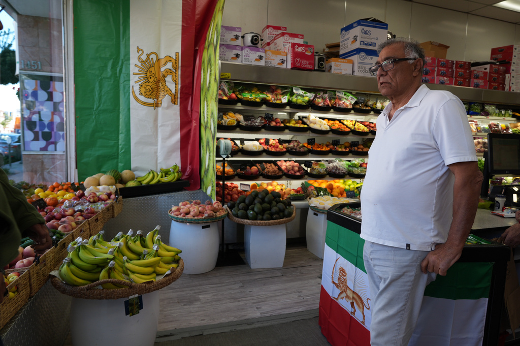 Farid, who gave only his first name, from Iran, works at Jordan Market, a Middle Eastern and Persian market along Westwood Boulevard, in the Westwood neighborhood of Los Angeles, pauses next to The Lion and Sun flags, the pre-revolution Iranian national flag, at the heart of the largest Iranian diaspora community in the United States, Monday, March 2, 2026. (AP Photo/Damian Dovarganes)