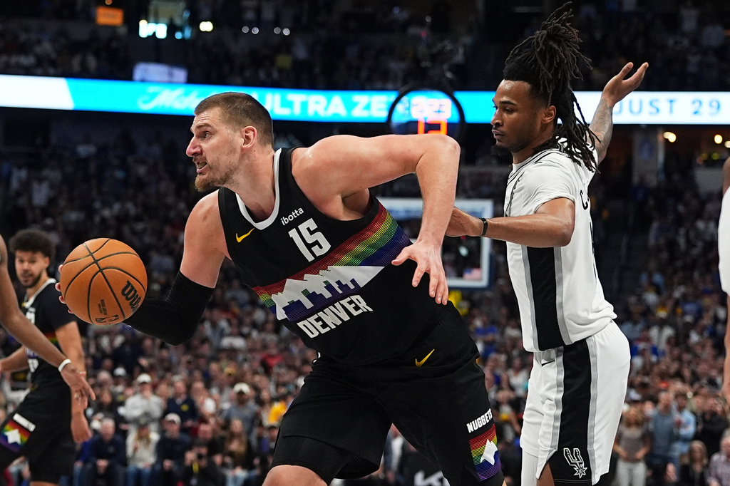 Denver Nuggets center Nikola Jokic, left, drives the lane past San Antonio Spurs guard Stephon Castle during overtime of an NBA basketball game Saturday, April 4, 2026, in Denver. (AP Photo/David Zalubowski)