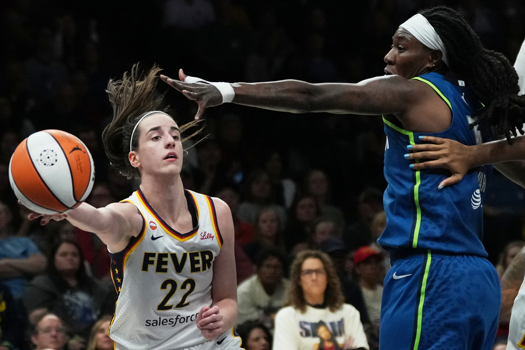 Indiana Fever guard Caitlin Clark (22) passes the ballaround Minnesota Lynx forward Natasha Howard, right, during the first half of a WNBA basketball game, Thursday, Sept. 24, 2026, in Minneapolis. (AP Photo/Ellen Schmidt)