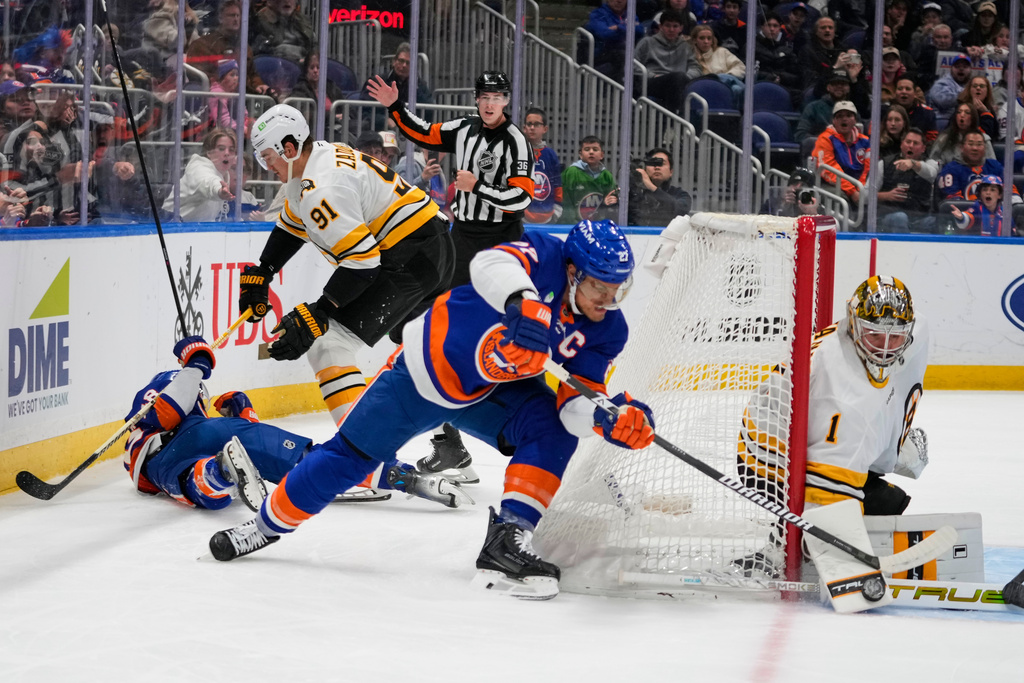 Boston Bruins goaltender Jeremy Swayman (1) stops a shot by New York Islanders' Anders Lee (27) as Boston Bruins' Nikita Zadorov (91) checks Matthew Schaefer during the second period of an NHL hockey game Tuesday, Nov. 4, 2025, at UBS Arena in Elmont, N.Y. (AP Photo/Frank Franklin II)