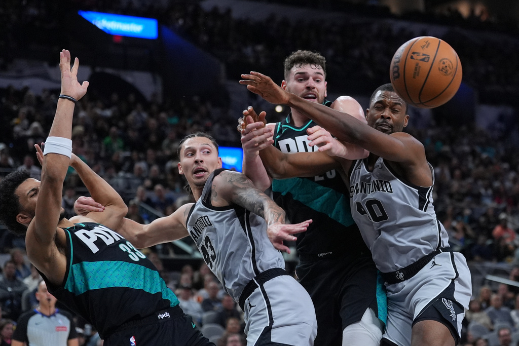 San Antonio Spurs forward Lindy Waters III (43) and forward Harrison Barnes (40) compete with Portland Trail Blazers forward Toumani Camara (33) and center Donovan Clingan (23) for a rebound during the first half of an NBA basketball game in San Antonio, Saturday, Jan. 3, 2026. (AP Photo/Eric Gay)
