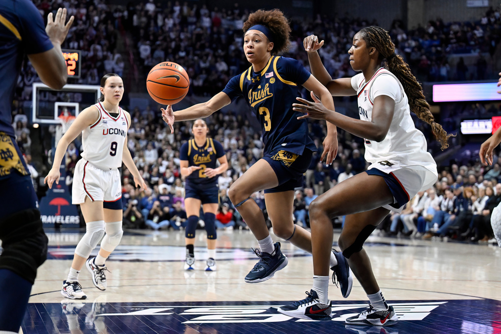 Notre Dame guard Hannah Hidalgo, center, passes the ball as UConn forward Serah Williams, right, defends in the first half of an NCAA college basketball game, Monday, Jan. 19, 2026, in Storrs, Conn. (AP Photo/Jessica Hill)
