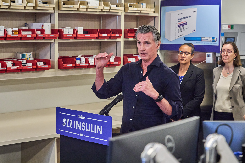 FILE - California Gov. Gavin Newsom announces CalRx-branded insulin glargine pens available next Jan. 1, 2026, at a suggested retail price of no more than $55 per five-pack, or $11 per pen, during a news conference at Cedar-Sinai's Mark Goodson pharmacy in Los Angeles Oct. 16, 2025. Secretary Kim Johnson, Cal HHS Agency, middle. (AP Photo/Damian Dovarganes, File)