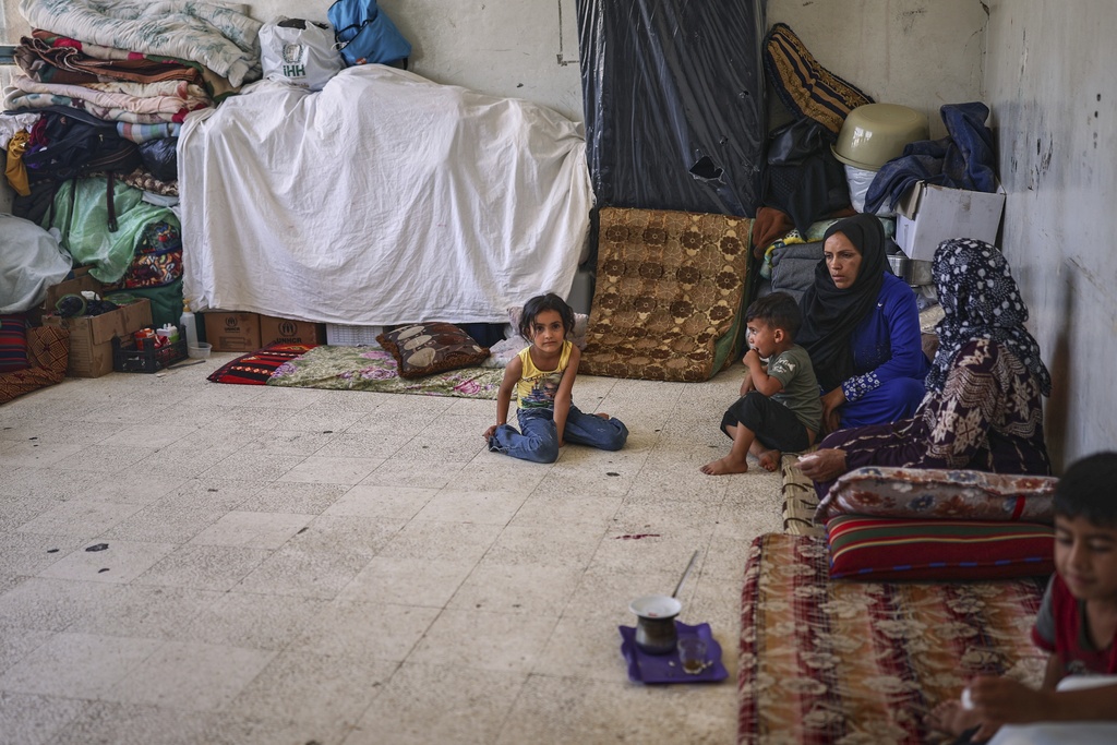 A family sits at a school sheltering displaced Syrian Bedouins from the Sweida region, forced from their homes after clashes between Druze militias and Bedouin groups, in the village of Abtaa in rural Daraa, Syria, Aug. 15, 2025. (AP Photo/Ghaith Alsayed)