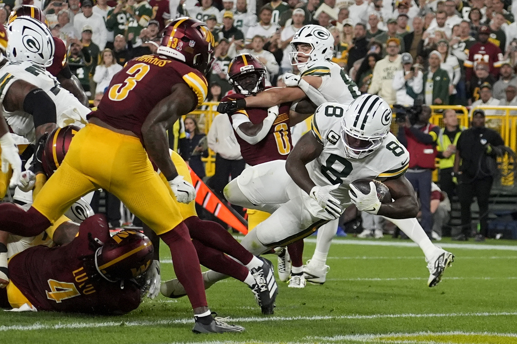Green Bay Packers running back Josh Jacobs (8) scores as Washington Commanders safety Will Harris (3) watches during the first half of an NFL football game Thursday, Sept. 11, 2025, in Green Bay, Wis. (AP Photo/Morry Gash)