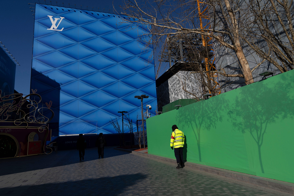 A security guard stands near a fence with a security camera at a shopping mall in Beijing, Saturday, Feb. 8, 2025. (AP Photo/Ng Han Guan)