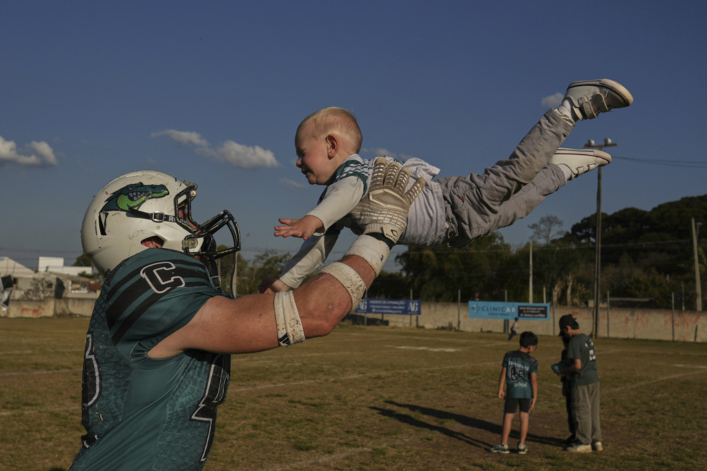 The Coritiba Crocodiles' Cleverson Kvas, a survivor of the 2024 team bus crash that killed three athletes, plays with his son Andre after a football game against the Brown Spiders in Curitiba, Brazil, Sunday, Aug. 17, 2025. (AP Photo/Andre Penner)
