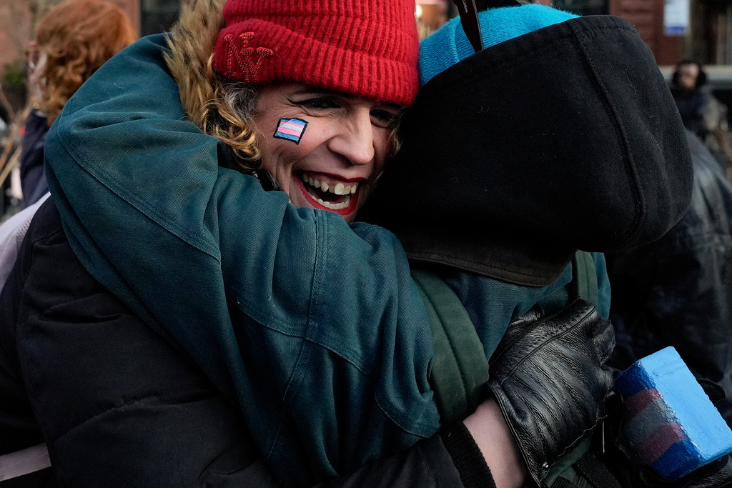 People react after protestors raised a rainbow flag on a pole in Christopher Park across the street from the Stonewall Inn, Thursday, Feb. 12, 2026, in New York, a few days after it was removed by the National Park Service to comply with guidance from the Trump administration. (AP Photo/Yuki Iwamura)