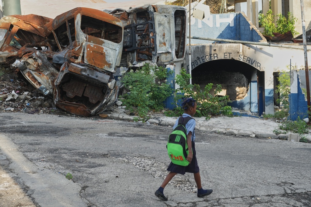 A student walks past a police station that was set on fire by armed gangs in the Carrefour Aeoport area of the Delmas neighborhood of Port-au-Prince, Haiti, Tuesday, Feb. 24, 2026. (AP Photo/Odelyn Joseph)