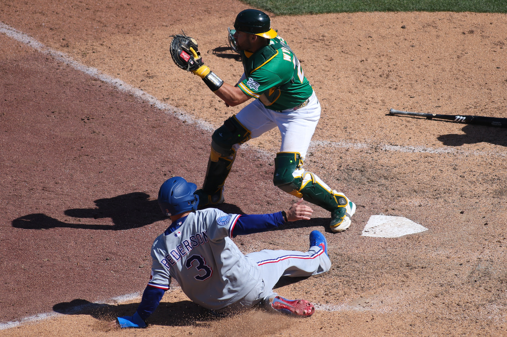 Texas Rangers' Joc Pederson (3) slides into home plate to score a run during the ninth inning of a baseball game against the Athletics, Thursday, April 16, 2026, in West Sacramento, Calif. (AP Photo/Scott Marshall)