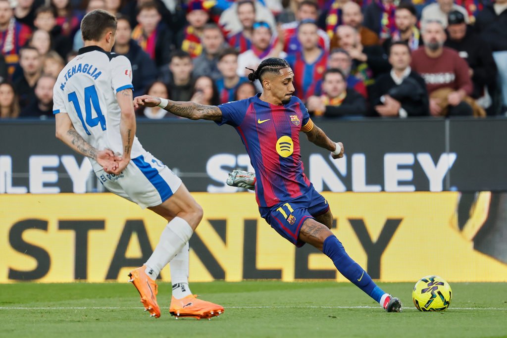 Barcelona's Raphinha, right, duels for the balls with Alaves' Nahuel Tenaglia during a Spanish La Liga soccer match between Barcelona and Alaves, in Barcelona, Spain, Saturday, Nov. 29, 2025. (AP Photo/Joan Monfort)