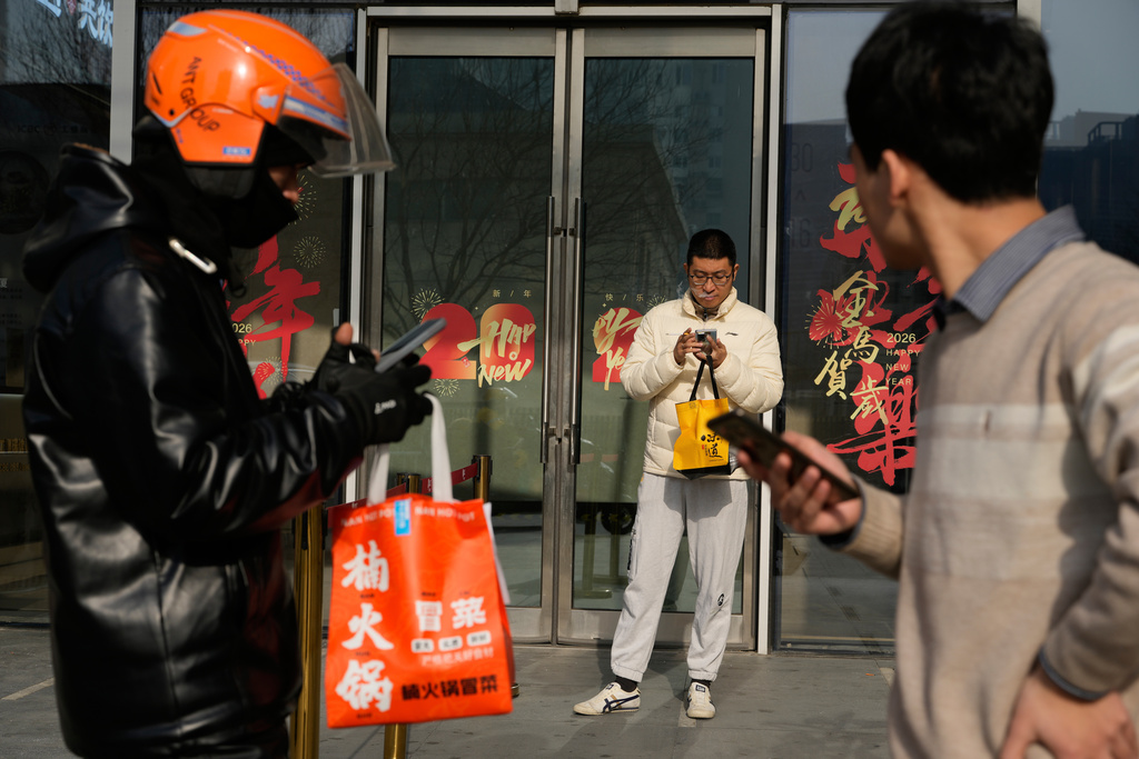 Workers stand outside a office building in Beijing, China, on Jan. 15, 2026. (AP Photo/Ng Han Guan)