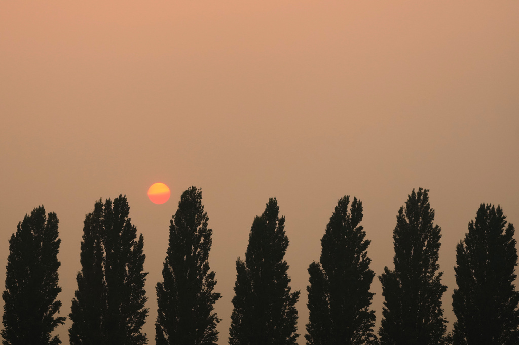 The sun begins to set behind lingering smoke from several wildfires in the state near Sprague, Wash., Tuesday, Aug. 4, 2026. (AP Photo/Lindsey Wasson)