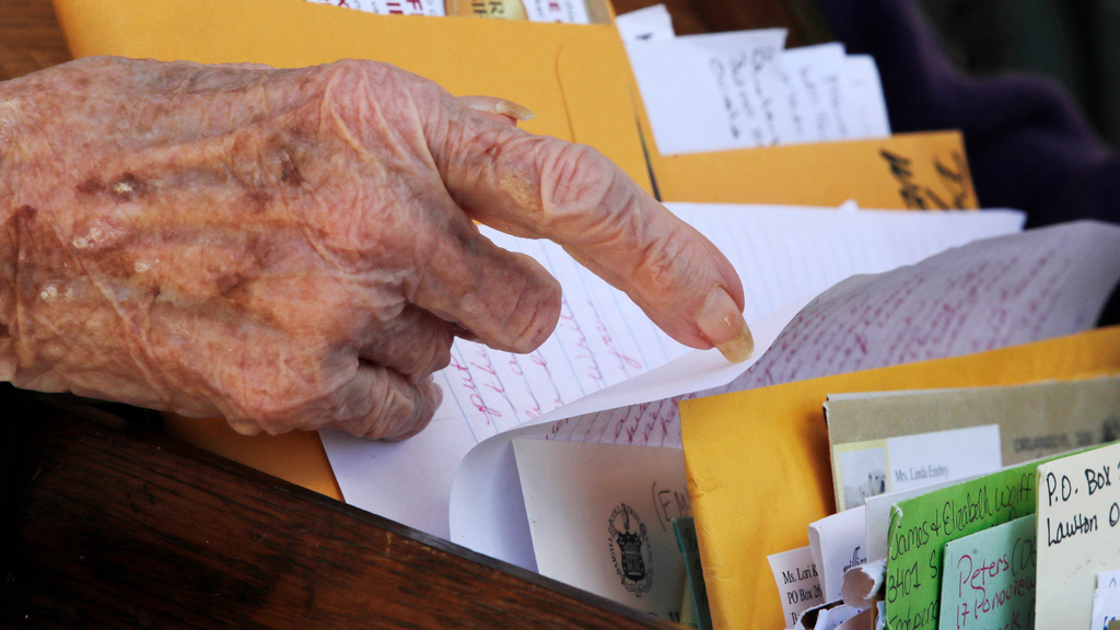 FILE - Flo Young, originally from Cambridge, Mass., browses through a box of a pen pal letters outside the Sullivan County Health Care nursing home in Unity, N.H., June 8, 2020. (AP Photo/Charles Krupa, File)