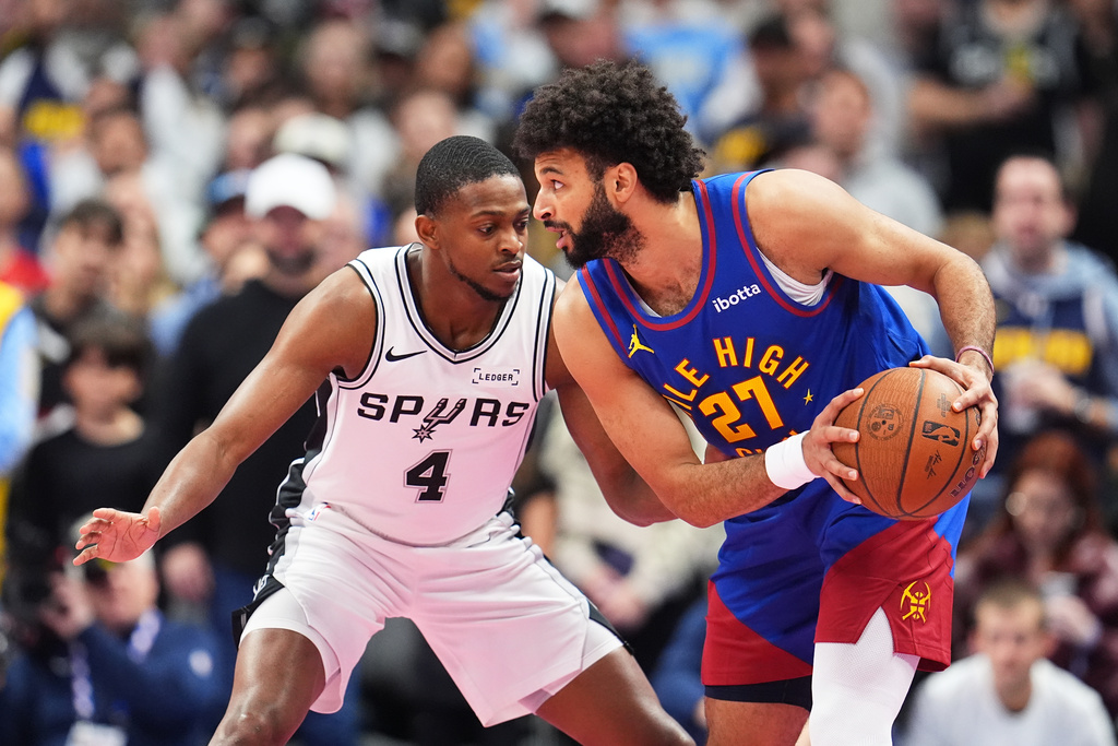 Denver Nuggets guard Jamal Murray, right, looks to pass the ball as San Antonio Spurs guard De'Aaron Fox defends in the first half of an NBA Cup basketball game Friday, Nov. 28, 2025, in Denver. (AP Photo/David Zalubowski)