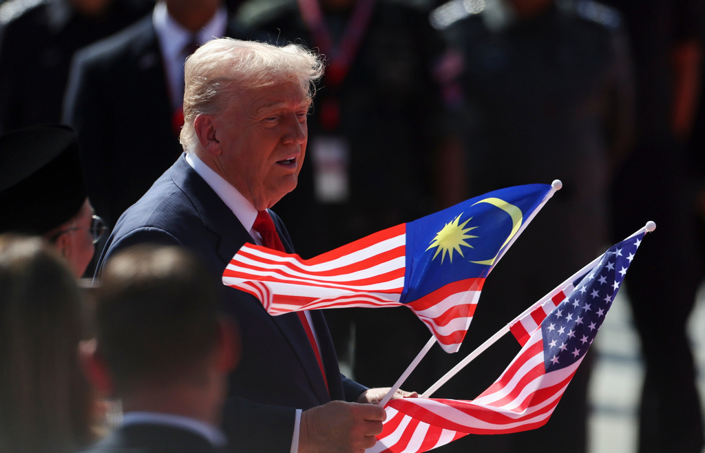 U.S. President Donald Trump holds the Malaysia and U.S. flags during a welcoming ceremony as he arrives at Kuala Lumpur International Airport to attend the 47th Association of Southeast Asian Nations (ASEAN) summit in Kuala Lumpur, Malaysia, Sunday, Oct. 26, 2025. (Hasnoor Hussain/Pool Photo via AP)