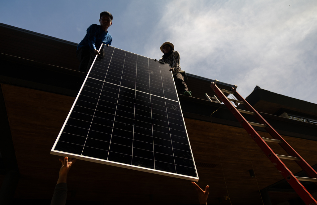 A team of solar installers haul a solar panel onto the roof of a home in Manila, Philippines, on April 30, 2026. (AP Photo/Anton L. Delgado)