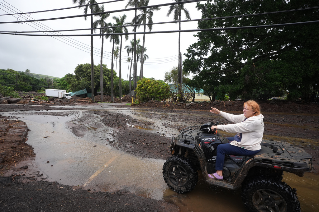 Peggy McKibbin looks at where floodwaters from nearby Hurricane Nolo run past widespread damage from last month's Hurricane Lala Sunday, Sept. 27, 2026, in Naalehu, Hawaii. (AP Photo/Gregory Bull)