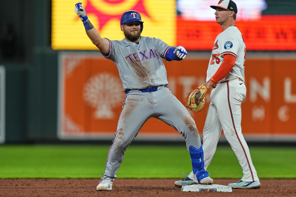 Texas Rangers' Jake Burger, left, celebrates after hitting a double during the ninth inning of a baseball game against the Baltimore Orioles, Monday, March 30, 2026, in Baltimore. (AP Photo/Stephanie Scarbrough)