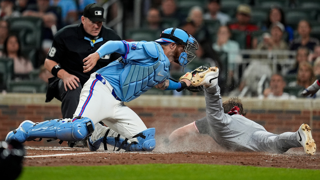 Cleveland Guardians' Daniel Schneemann (10) is safe at home plate against Atlanta Braves catcher Jonah Heim (20) inning of a baseball game, Saturday, April 11, 2026, in Atlanta. (AP Photo/Mike Stewart)