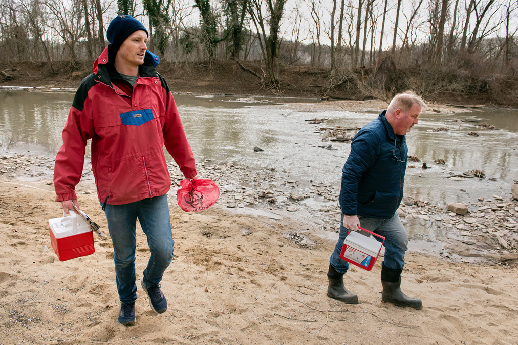 Potomac River Keeper Dean Naujoks, right, and volunteer water quality River Keeper Evan Quinter, carry coolers containing samples of river water which will be checked for Ecoli, alongside the site where a massive pipe rupture has sent sewage spilling into the Potomac River, in Glen Echo, Md., Friday, Jan. 23, 2026. (AP Photo/Cliff Owen)