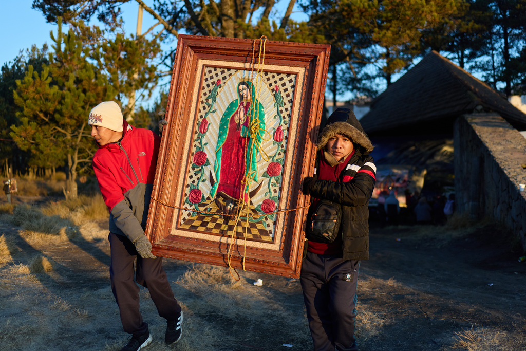 FILE - Pilgrims carry a framed image of the Virgin of Guadalupe through the mountain pass Paso de Cortes, on their way to Mexico City, Dec. 10, 2025, as millions prepare to flock to the capital for her feast day. (AP Photo/Claudia Rosel, File)