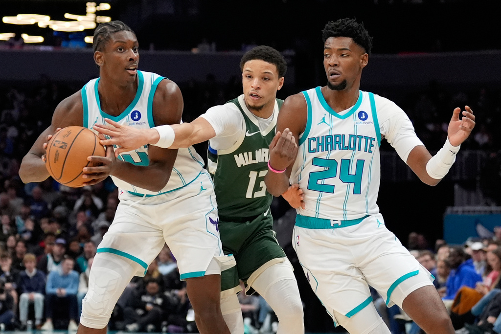 Milwaukee Bucks guard Ryan Rollins vies for the ball between Charlotte Hornets forward Moussa Diabate, left, and forward Brandon Miller during the first half of an NBA basketball game, Monday, Dec. 29, 2025, in Charlotte, N.C. (AP Photo/Chris Carlson)
