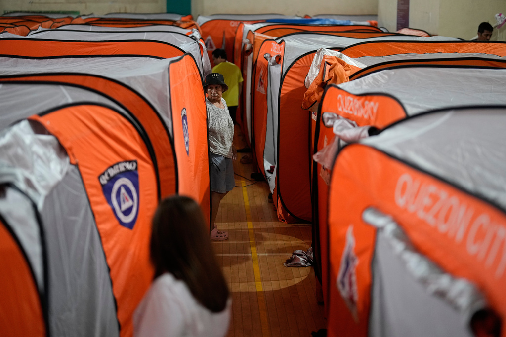 A woman walks beside tents at an evacuation center as Typhoon Fung-wong enters the country on Sunday, Nov. 9, 2025 in Quezon city, Philippines. (AP Photo/Aaron Favila)