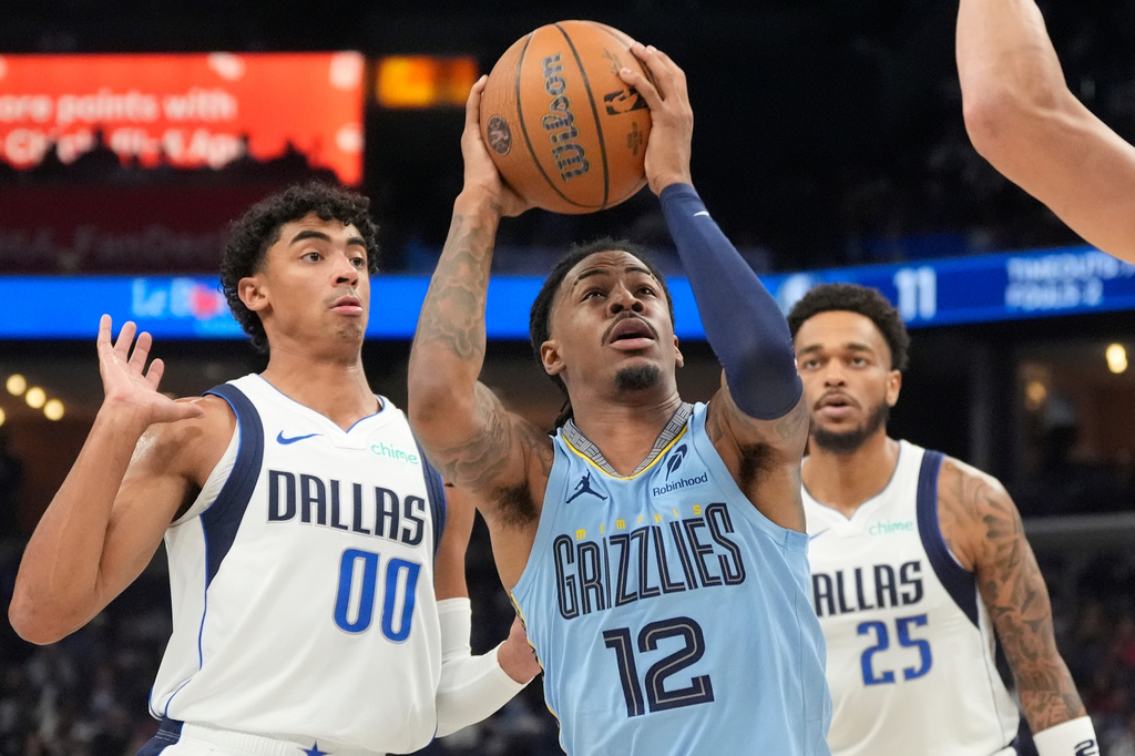 Memphis Grizzlies guard Ja Morant (12) goes to the basket past Dallas Mavericks guard Max Christie (00) and forward P.J. Washington (25) during the first half of an NBA Cup basketball game Friday, Nov. 7, 2025, in Memphis, Tenn. (AP Photo/George Walker IV)