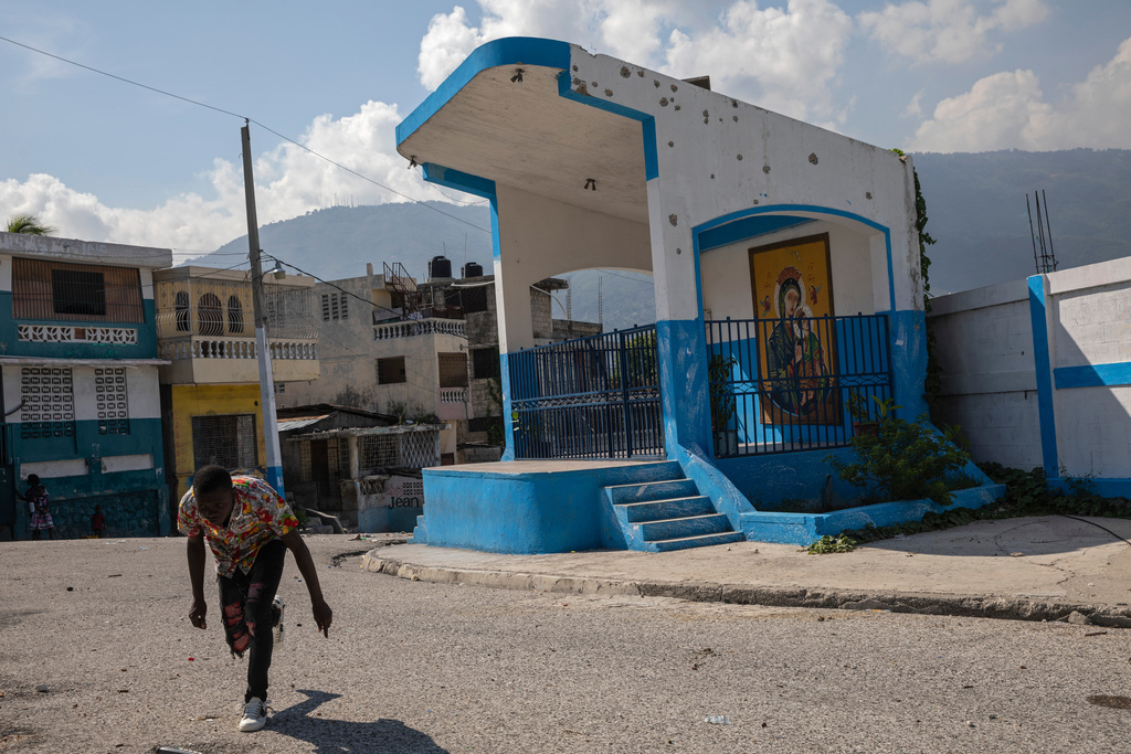 FILE - A man runs for cover as he crosses a barricaded street in the gang-controlled Bel Air neighborhood of Port-au-Prince, Haiti, Sept. 25, 2021. (AP Photo/Rodrigo Abd, File)