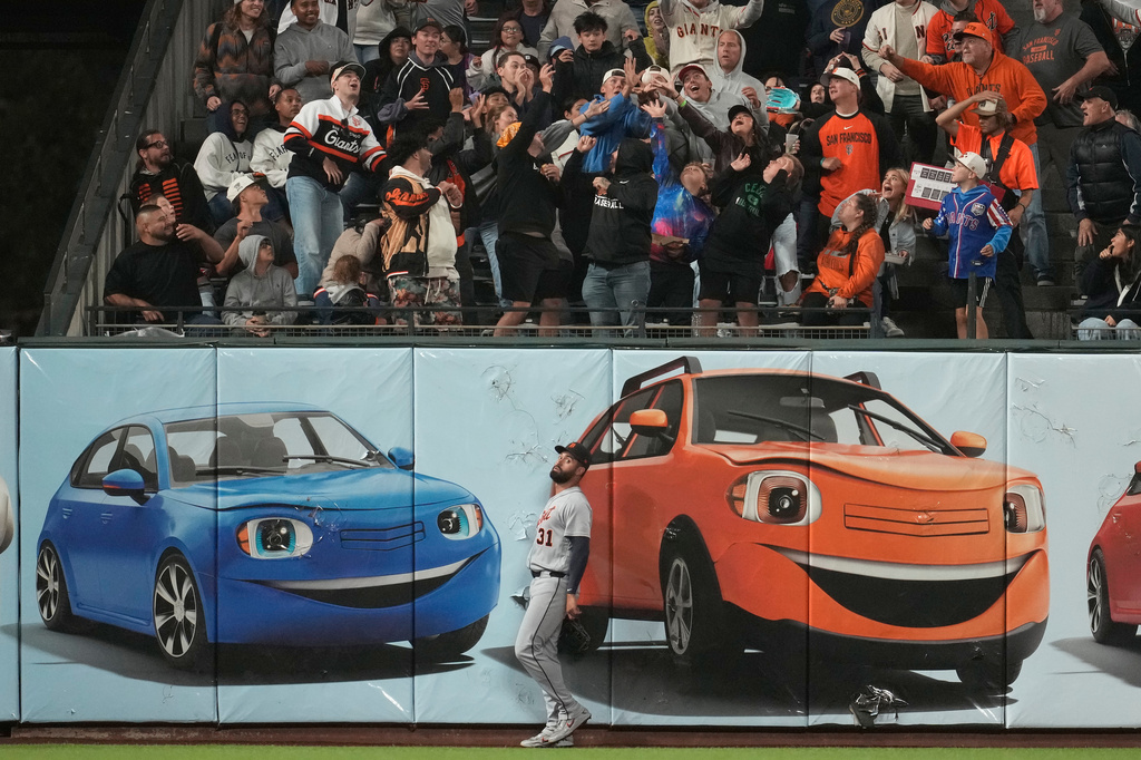 Detroit Tigers left fielder Riley Greene, bottom, reacts as fans reach for a home run hit by San Francisco Giants' Willy Adames during the fifth inning of a baseball game, Friday, Aug. 7, 2026, in San Francisco. (AP Photo/Jeff Chiu)