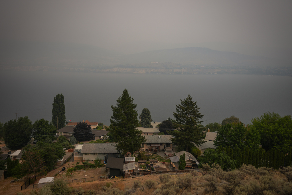 Houses are seen overlooking Okanagan Lake as smoke from the Bald Range wildfire blankets the area, in Penticton, British Columbia, Sunday, Aug. 9, 2026. (Darryl Dyck/The Canadian Press via AP)