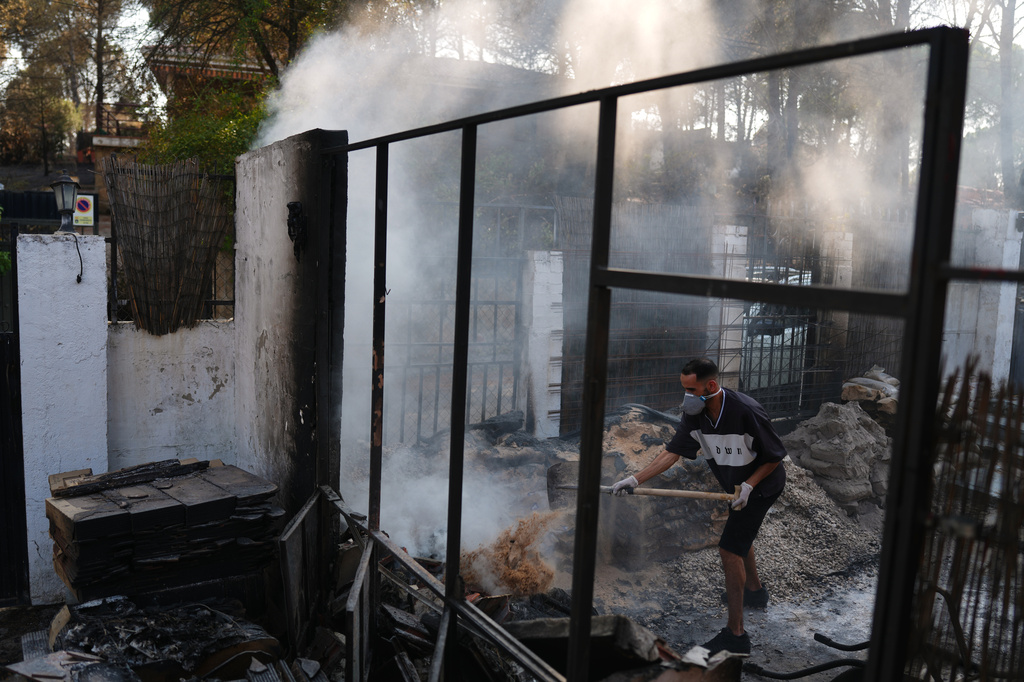 Moha Haddad tries to put out a fire at his home as a wildfire continues to spread near Navas del Rey, Ávila province, Spain, Tuesday, July 28, 2026. (AP Photo/Manu Fernandez)