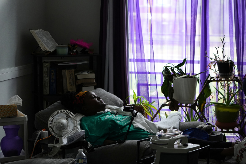 Ebony Payne, a disability advocate, looks through the window of her living room after an interview in Chicago, Ill., on Thursday, Sept. 10, 2026. Payne, a Chicago-based disability advocate who is quadriplegic, was a plaintiff in a lawsuit against “Deb’s law,″ contending it discriminates against people with disabilities. (AP Photo/Luis Andres Henao)