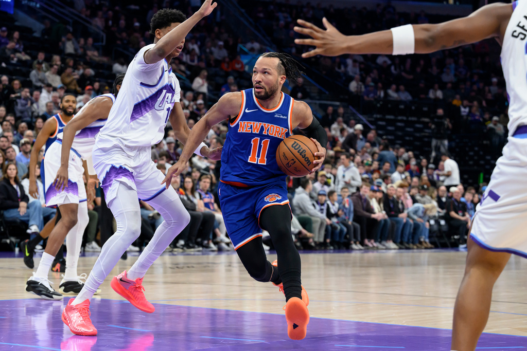 New York Knicks guard Jalen Brunson, center, drives to the basket guarded by Utah Jazz guard Ace Bailey, center left, during the first half of an NBA basketball game, Wednesday, March 11, 2026, in Salt Lake City. (AP Photo/Tyler Tate)