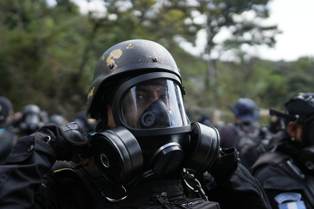 An anti-riot policeman adjusts his gas mask outside the Preventivo Zona 18 prison during a operation to free guards taken hostage and retake control of the facility in Guatemala City, Sunday, Jan. 18, 2026. (AP Photo/Emmanuel Andres)