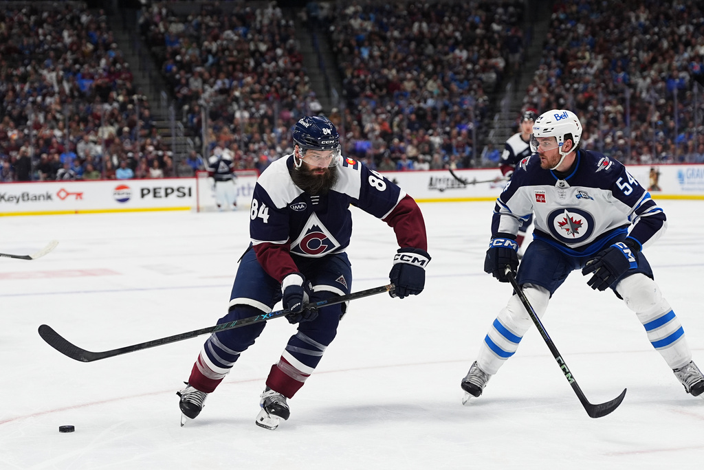 Colorado Avalanche defenseman Brent Burns, left, drives past Winnipeg Jets defenseman Dylan Samberg in the third period of an NHL hockey game Saturday, March 28, 2026, in Denver. (AP Photo/David Zalubowski)