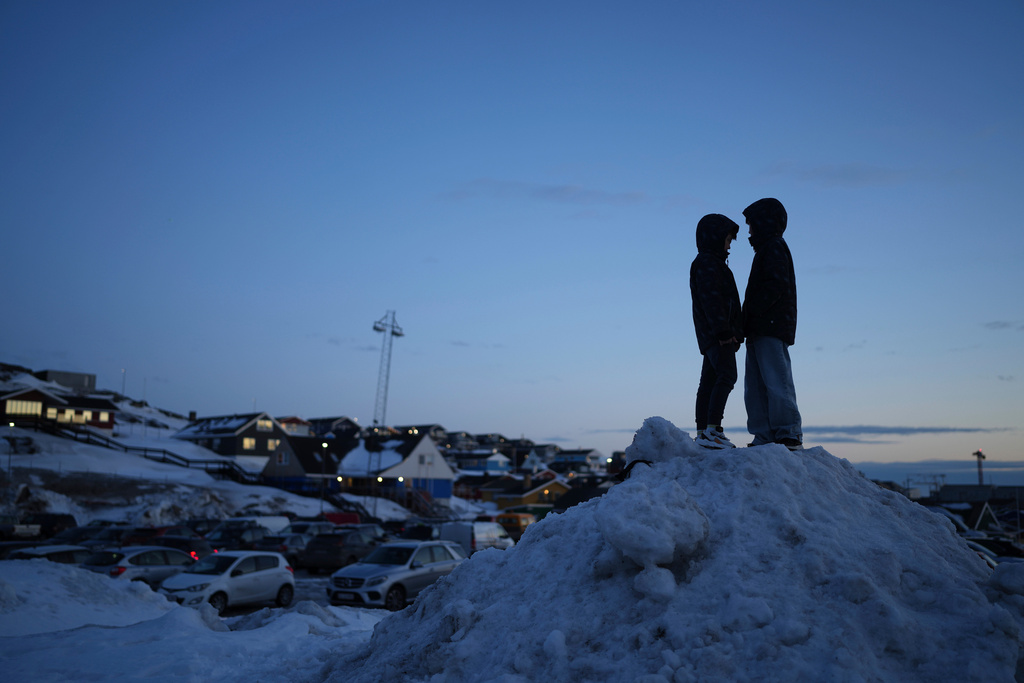 FILE - Locals stand on a pile of snow during parliamentary elections, in Nuuk, Greenland, on March 11, 2025. (AP Photo/Evgeniy Maloletka, File)