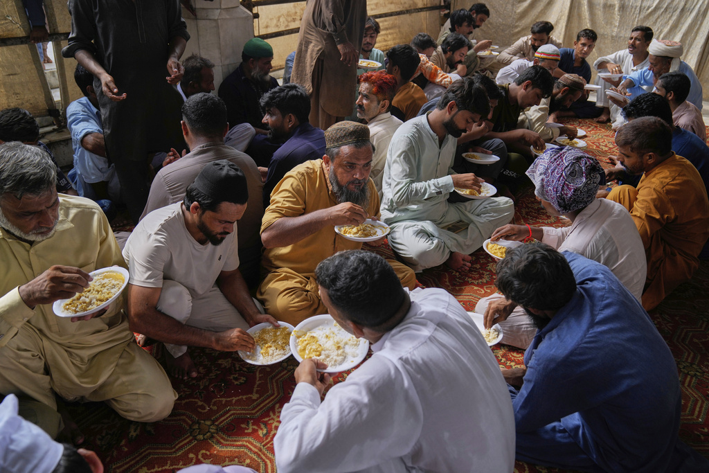Devotees eat food during celebrations of the three-day annual festival or 'Urs' of mystic and scholar, Hazrat Ali Hajveri, popularly known as Data Ganj Bakhsh at his shrine, in Lahore, Pakistan, Friday, Aug. 15, 2025. (AP Photo/K.M. Chaudary)