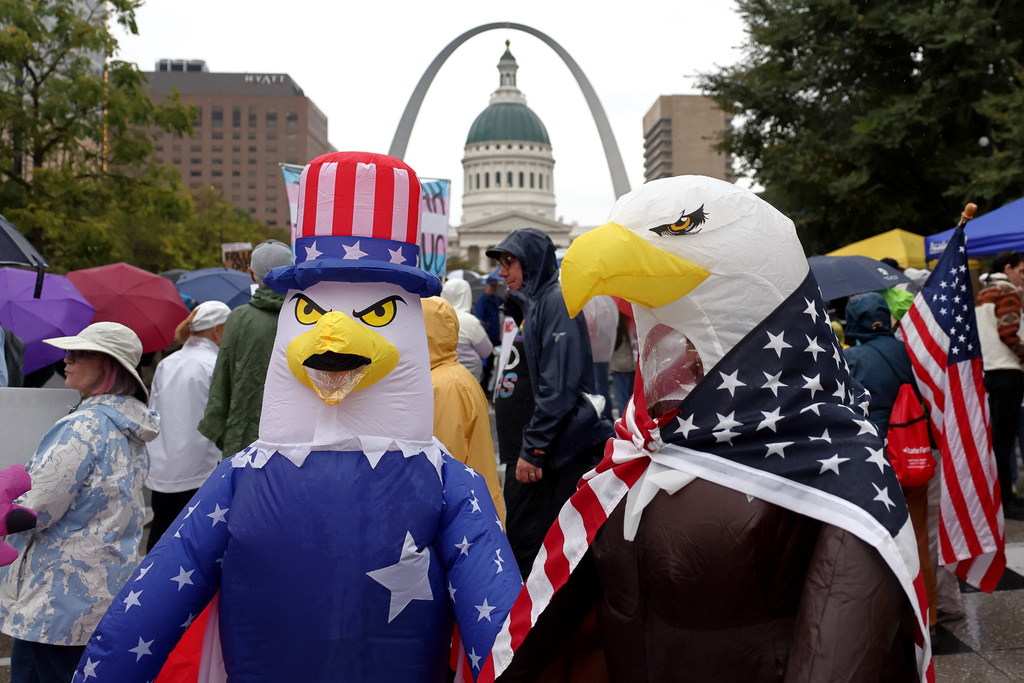 Demonstrators wearing inflatable bald eagle costumes gather in Kiener Plaza during the "No Kings" protest in St. Louis, with the Gateway Arch in the background, on Saturday, Oct. 18, 2025. (David Carson/St. Louis Post-Dispatch via AP)