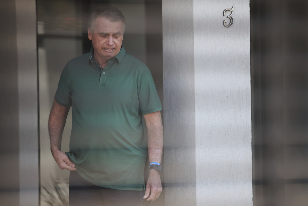 Brazil's former President Jair Bolsonaro stands at the entrance of his home where he is under house arrest in Brasilia, Brazil, Thursday, Sept. 11, 2025. (AP Photo/Luis Nova)