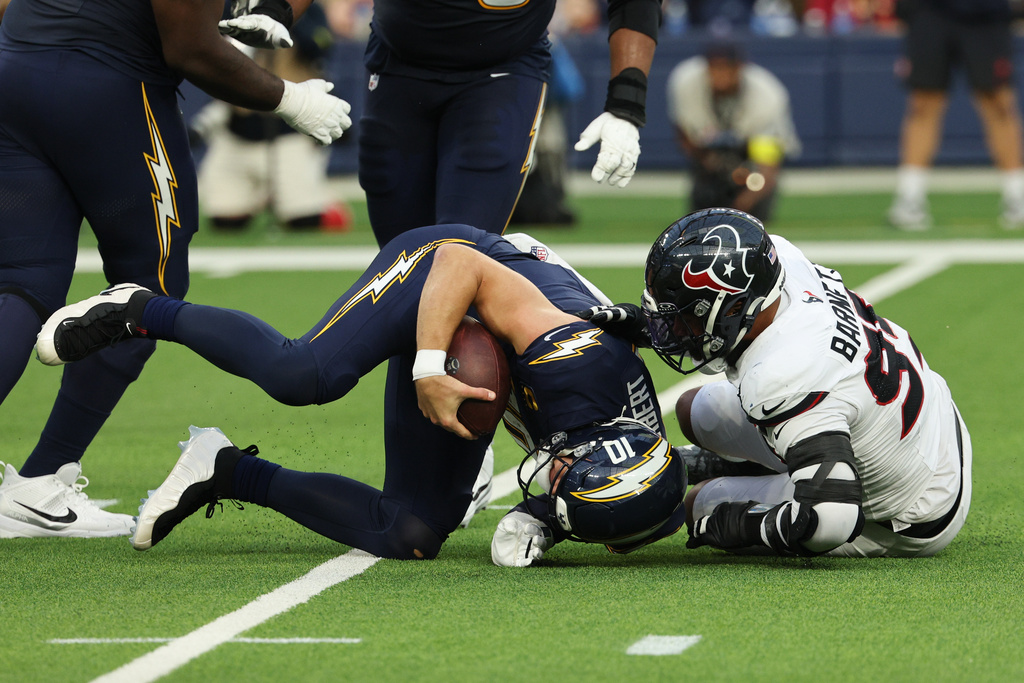 Los Angeles Chargers quarterback Justin Herbert (10) is sacked by Houston Texans defensive end Derek Barnett (95) during the second half of an NFL football game Saturday, Dec. 27, 2025, in Inglewood, Calif. (AP Photo/Kevork Djansezian)