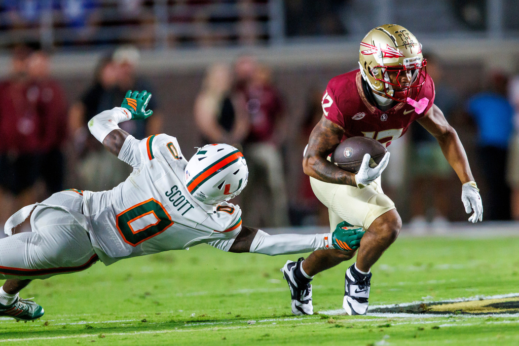 Miami defensive back Keionte Scott (0) reaches to stop Florida State running back Jaylin Lucas (12) during the first half of an NCAA college football game Saturday, Oct. 4, 2025, in Tallahassee, Fla. (AP Photo/Colin Hackley)